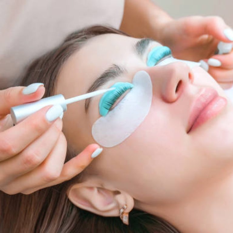 Young woman receiving eyelash lamination procedure in a beauty salon, close up