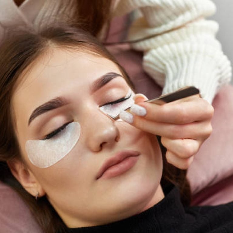 cosmetologist removes glue cotton tape under eye. Eyelash extension procedure